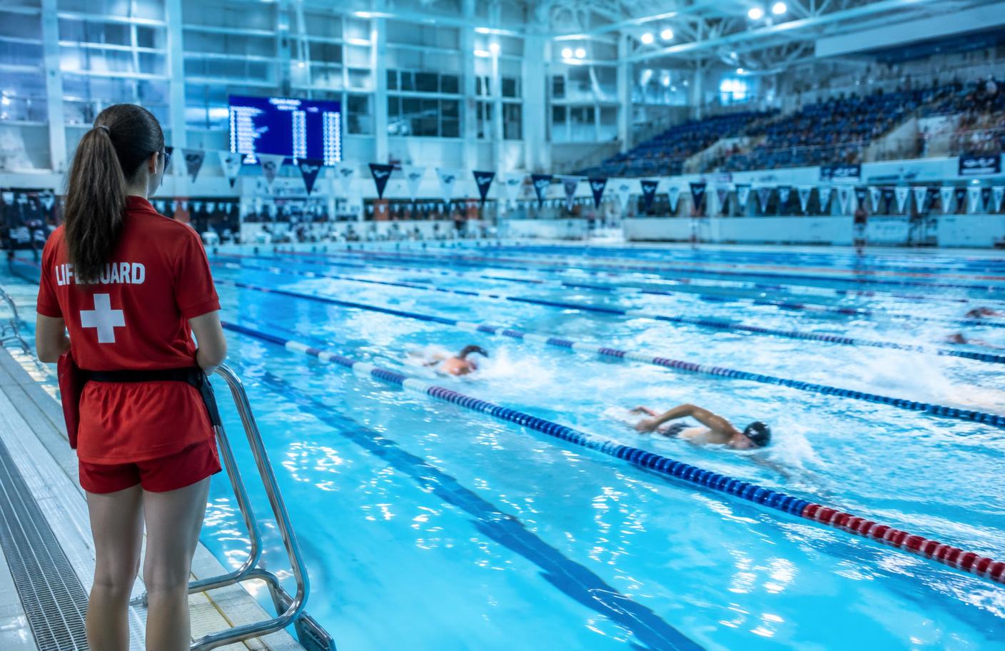 Lifeguard observing swimmers racing during a swimming gala